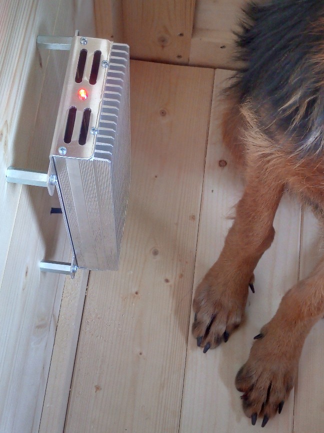 radiatore riscaldante linea Sofia appeso alla paretina della cuccia e sullo sfondo le zampe del mi cane accanto al teporedella stufetta.